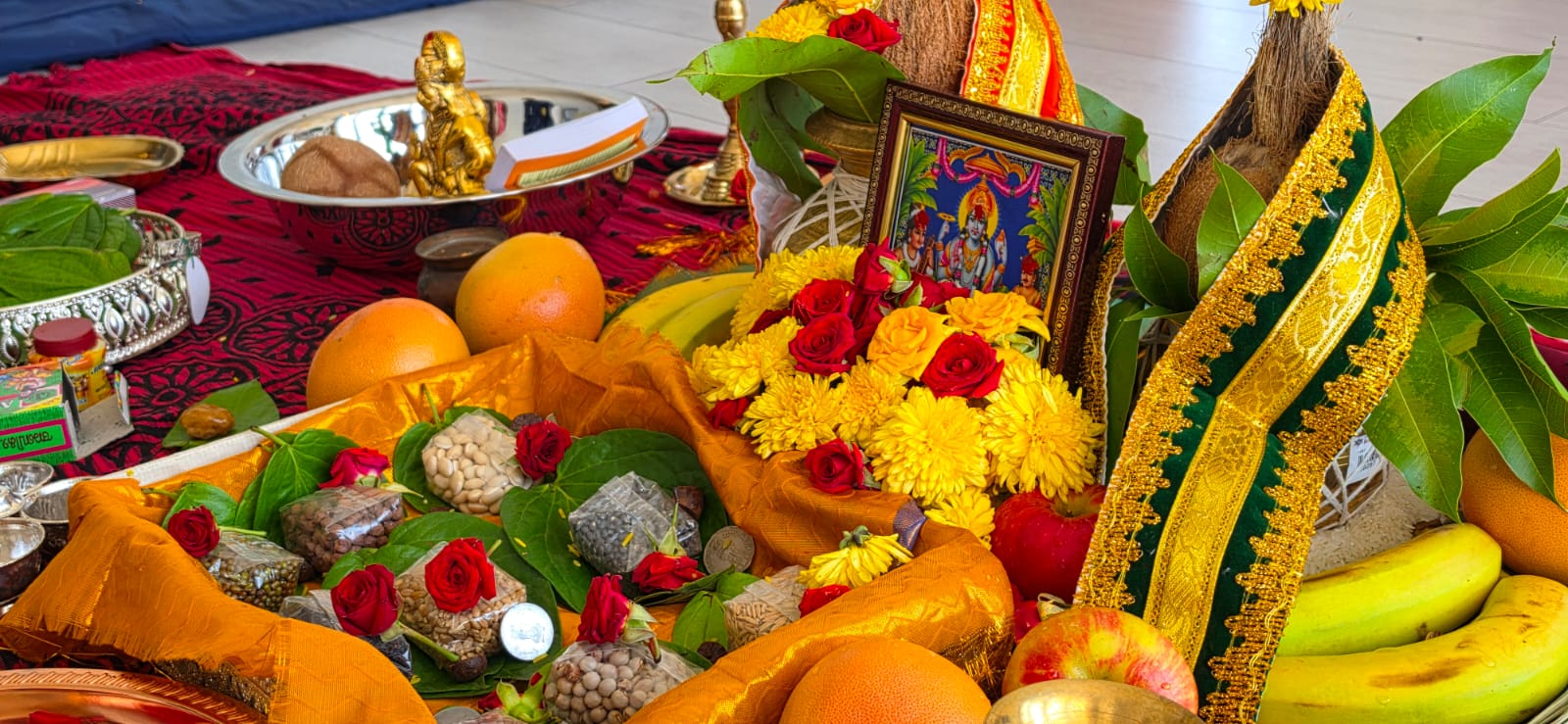 Puja tray with betel leaves, fruits, roses and grains arranged for the ritual