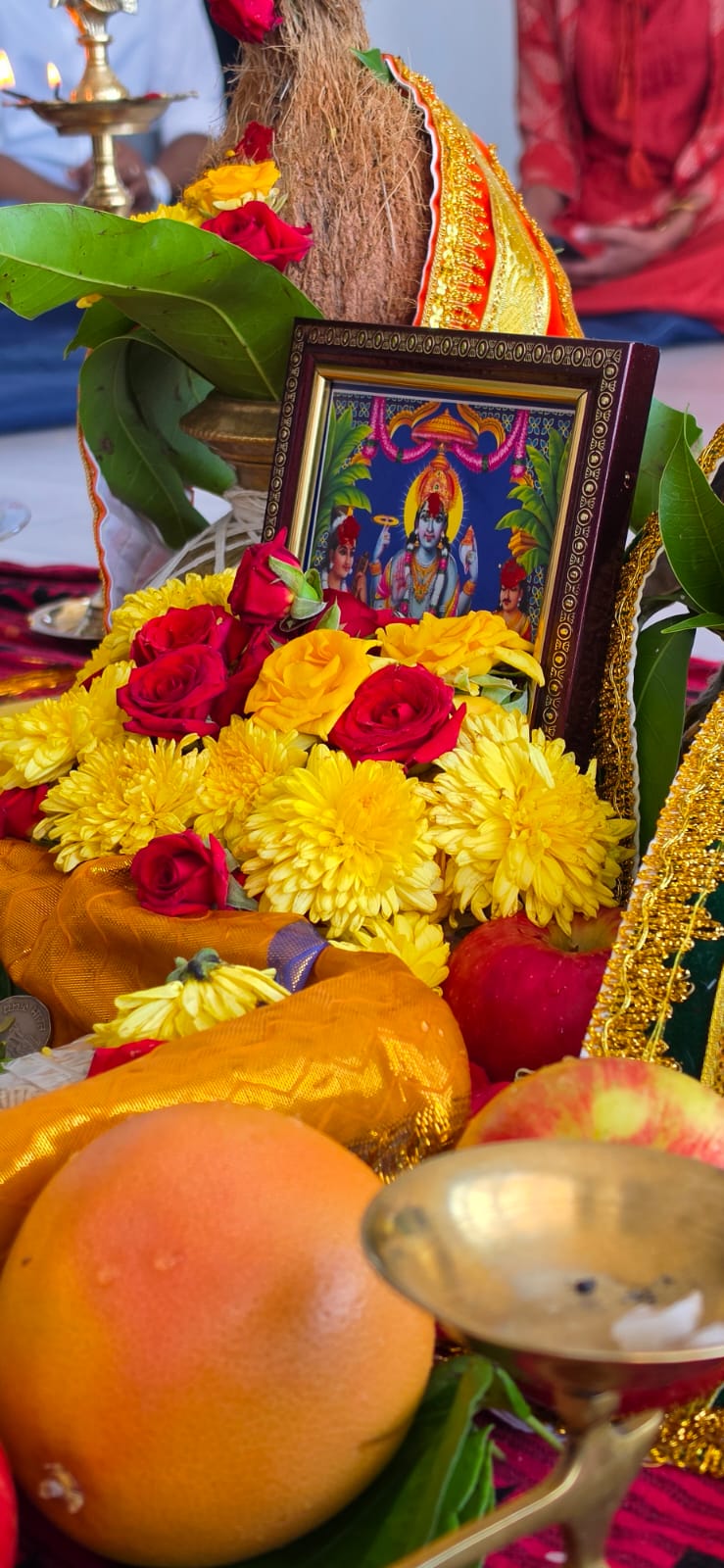 Satyanarayan Swami portrait surrounded by flowers, coconuts and mango leaves